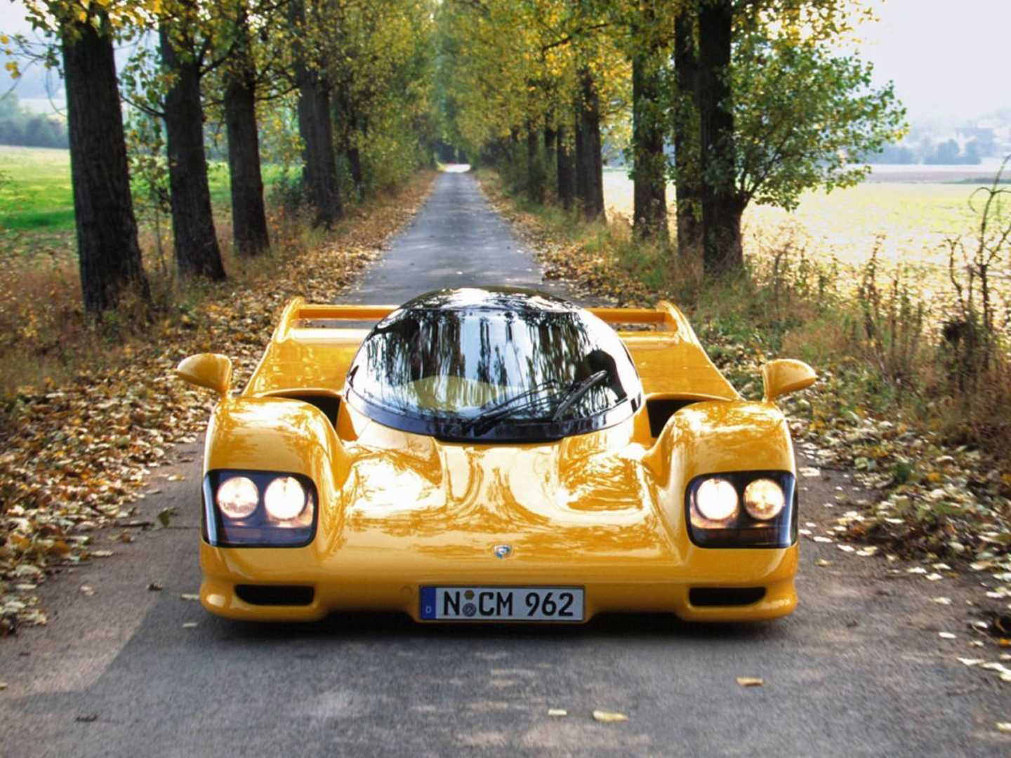 962 Le Mans jaune de face en pleine campagne avec les phares allumés