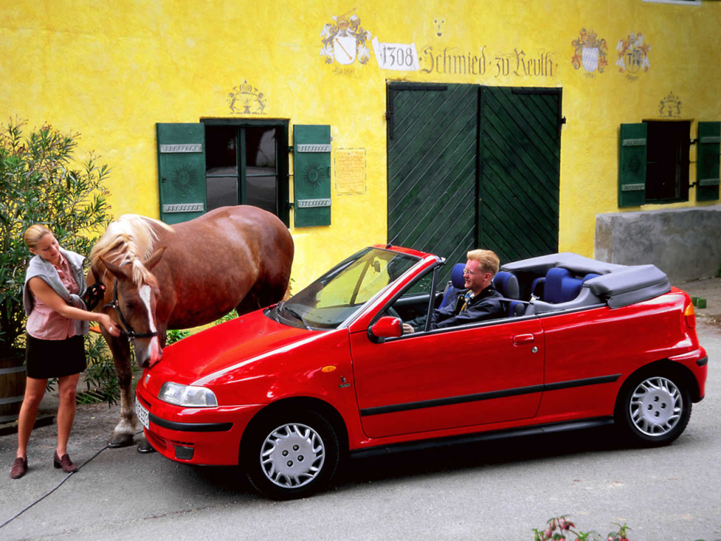 Punto Cabriolet rouge dans la rue, un cheval se tient devant la voiture