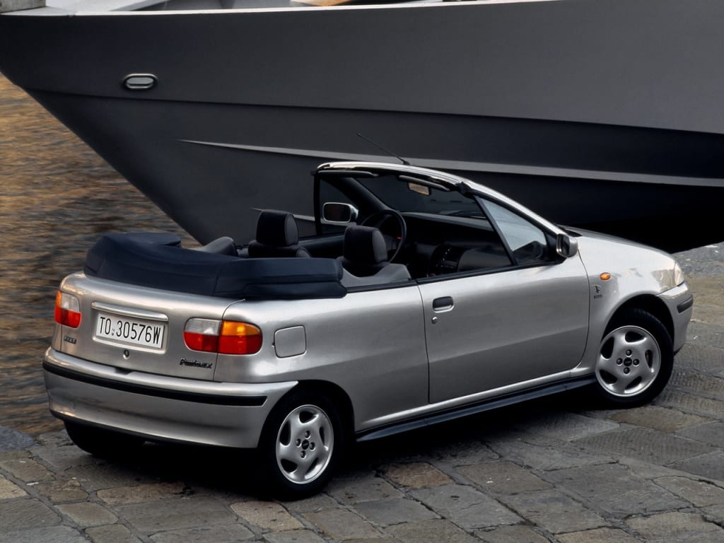 Punto Cabriolet grise de trois quarts arrière devant un bateau