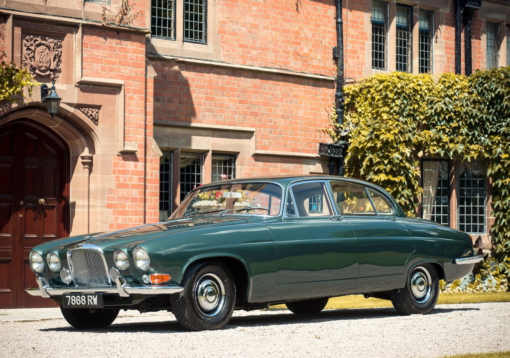 Jaguar Mark X verte devant une bâtisse