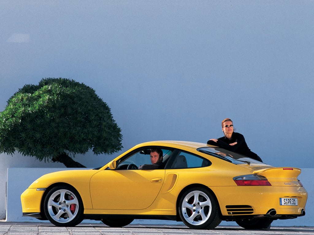 Porsche 911 "996" jaune de profil avec une personne au volant