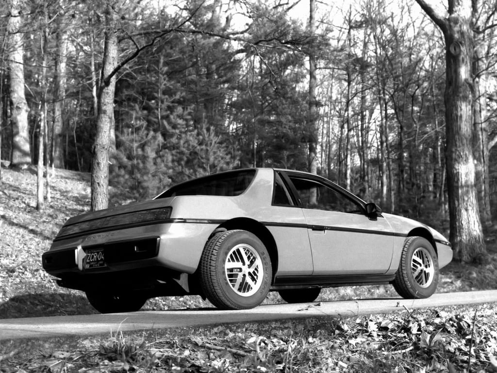 La Pontiac Fiero dans une forêt vue de trois quarts arrière