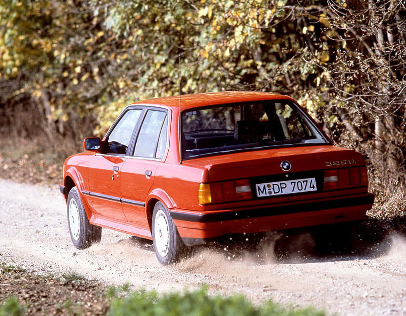 Vue arrière de la BMW 325iX E30 roulant sur un sentier