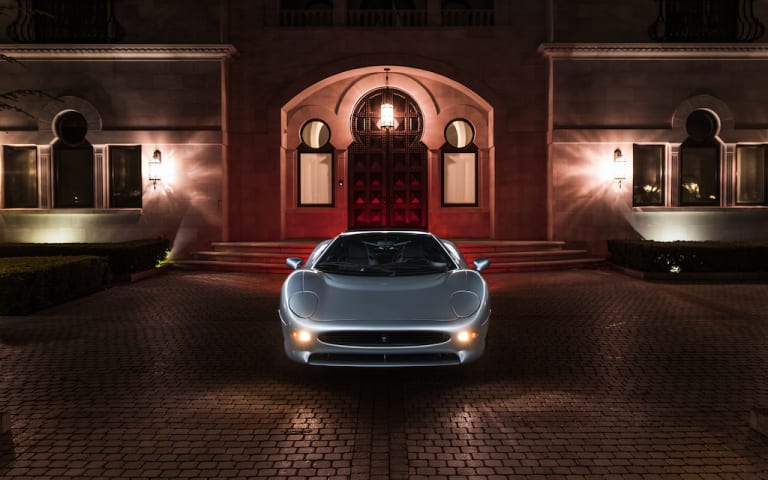 Vue de face de la Jaguar XJ220 dans la cour d'un palace de nuit