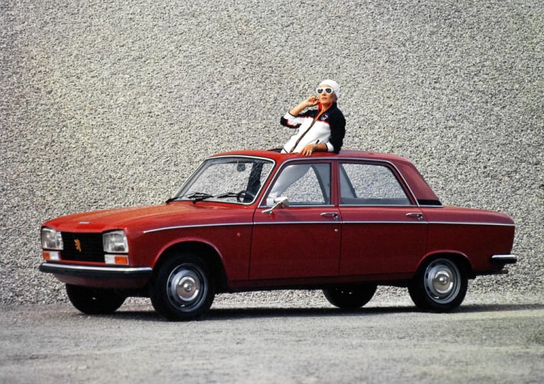 Peugeot 304 S rouge avec une personne faisant sortir sa tête du toit ouvrant