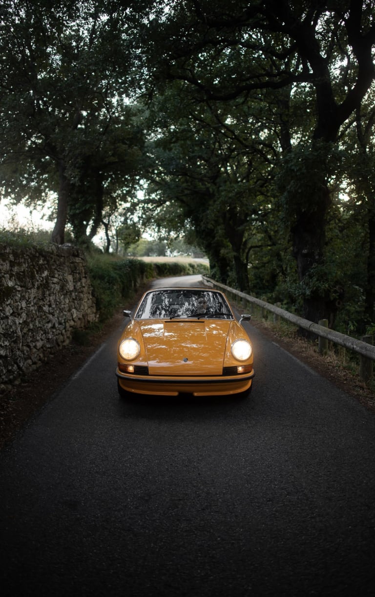 La Porsche de Vincent sur la route avec les phares allumés