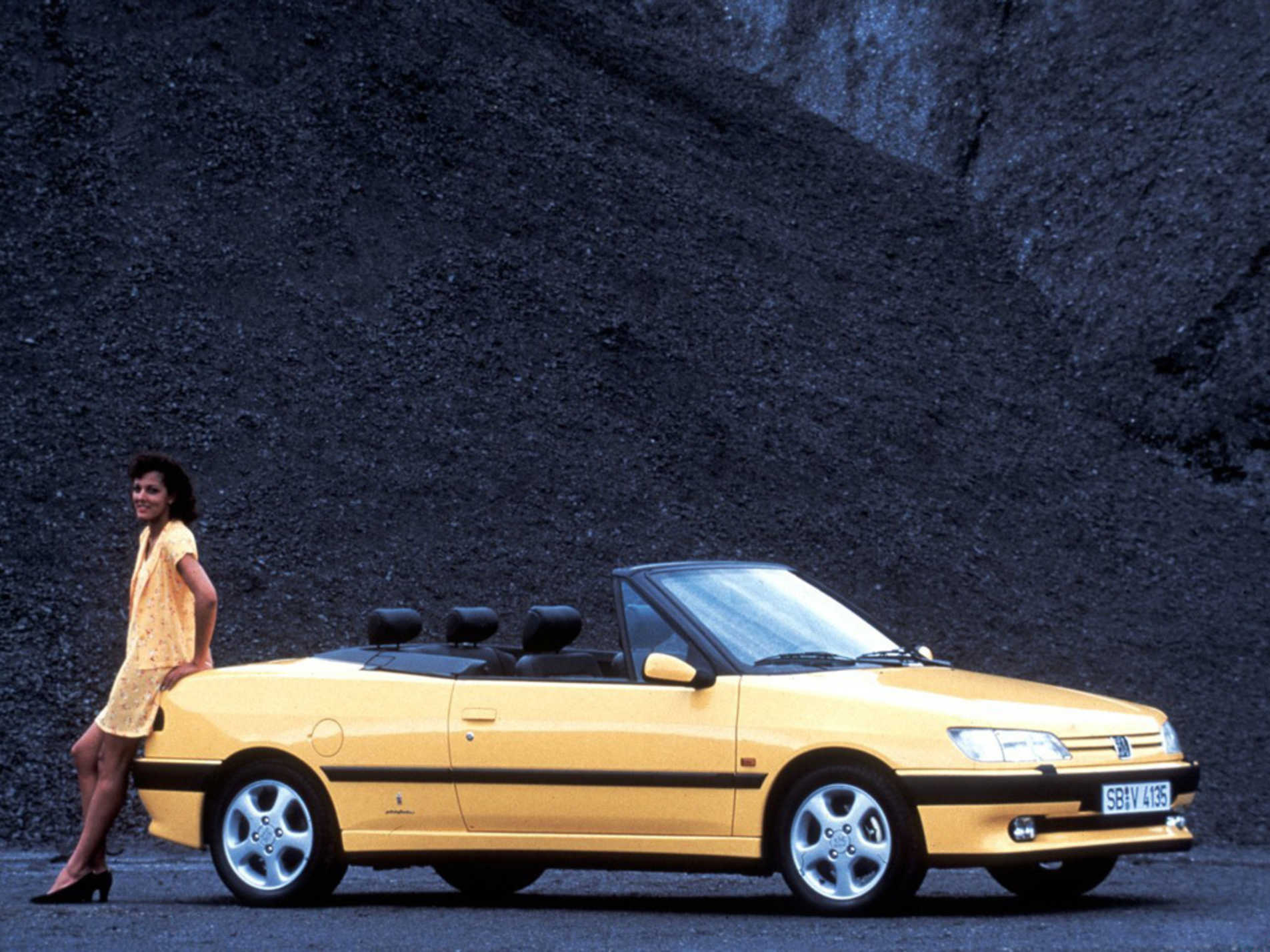 Peugeot 306 Cabriolet jaune avec une femme s'adossant à l'arrière de l'auto