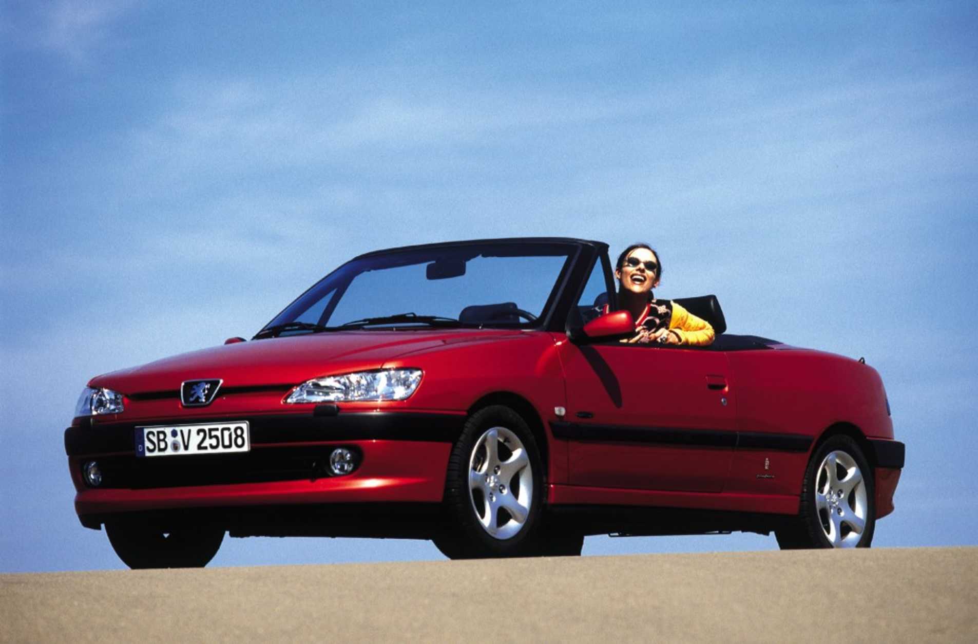 Peugeot 306 Cabriolet rouge avec une femme assise et souriante côté conducteur