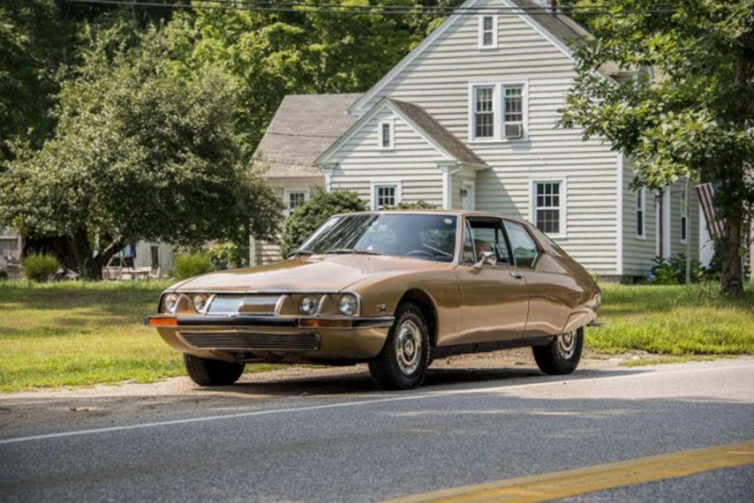 Citroën SM de couleur ocre vue devant une maison